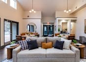 Thumbnail 9 of 10 - A living room with a grey couch and a round mirror on the wall.