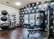 Thumbnail 6 of 10 - A gym with a checkered wallpaper and a variety of exercise equipment.