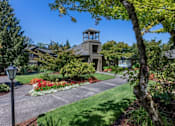 Thumbnail 1 of 10 - A house with a tower-like structure on the roof is surrounded by a well-manicured garden.