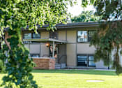 Thumbnail 2 of 24 - A house with a green lawn and trees in front.