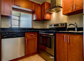 Thumbnail 15 of 23 - A kitchen with wooden cabinets and black countertops.