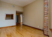 Thumbnail 14 of 23 - A room with wooden floors and a brick column on the wall.