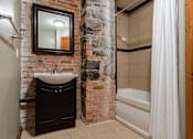 Thumbnail 17 of 23 - A bathroom with a stone wall and a white shower curtain.
