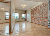 Thumbnail 11 of 23 - A room with wooden floors and a brick wall.