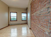 Thumbnail 7 of 23 - A room with a brick wall and wooden flooring.