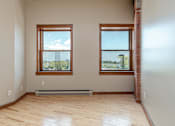 Thumbnail 9 of 23 - A room with wooden floors and two windows.