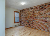 Thumbnail 10 of 23 - A room with a brick wall and wooden flooring.