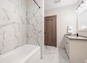 Thumbnail 27 of 39 - A white marble bathroom with a wooden door.