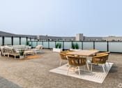 Thumbnail 33 of 39 - A patio with a table and chairs is set up on a rooftop.