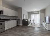 Thumbnail 9 of 11 - A modern kitchen with white cabinets and a grey sofa.