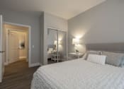 Thumbnail 3 of 11 - A bedroom with a large bed and a nightstand with a lamp.