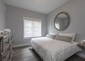 Thumbnail 10 of 11 - A bedroom with a bed, dresser, mirror, and window.