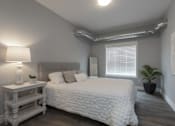 Thumbnail 5 of 11 - A bedroom with a white bed and a lamp on a nightstand.