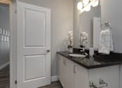 Thumbnail 6 of 11 - A white door is open to a bathroom with a sink and mirror.