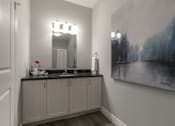 Thumbnail 7 of 11 - A bathroom with a grey cabinet and a painting on the wall.