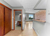 Thumbnail 21 of 23 - A long hallway with a doorway leading to a bathroom.