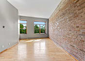Thumbnail 20 of 23 - A room with wooden floors and a brick wall.