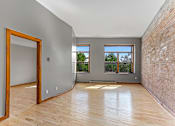 Thumbnail 16 of 23 - A room with wooden floors and a brick wall.