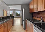 Thumbnail 22 of 23 - A kitchen with wooden cabinets and a black countertop.