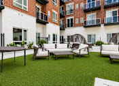 Thumbnail 39 of 40 - A patio with a table and chairs is surrounded by a brick building.