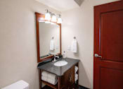 Thumbnail 14 of 20 - A bathroom with a toilet, sink, mirror, and towel rack.