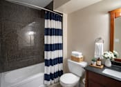 Thumbnail 13 of 20 - A bathroom with a white toilet, a sink, and a shower with a blue and white striped shower curtain.