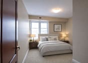 Thumbnail 15 of 20 - A bedroom with a large bed and two nightstands with lamps.