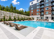 Thumbnail 3 of 40 - A swimming pool with lounge chairs and a building in the background.