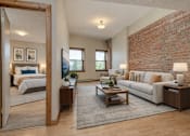 Thumbnail 5 of 29 - A living room with a white couch and a brick wall.