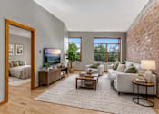 Thumbnail 2 of 29 - A living room with a grey couch, a wooden coffee table, and a large mirror.