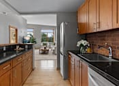 Thumbnail 7 of 29 - A kitchen with wooden cabinets and a black countertop.