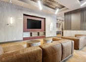 Thumbnail 16 of 34 - A modern living room with brown leather sofas and a flat screen TV at The Woods at 180 Kanata Avenue Apartments, Kanata, ON