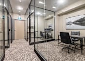 Thumbnail 25 of 28 - A glass walled office with a black chair and a framed picture on the wall.