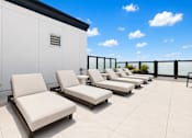 Thumbnail 10 of 40 - A row of white lounge chairs are arranged on a patio.
