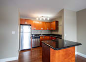 Thumbnail 17 of 20 - A kitchen with wooden cabinets and a black counter top.