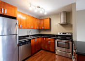 Thumbnail 18 of 20 - A modern kitchen with wooden cabinets and stainless steel appliances.
