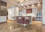 Thumbnail 11 of 34 - A modern kitchen with a wooden floor and a central island at The Woods at 180 Kanata Avenue Apartments, Kanata, Ontario