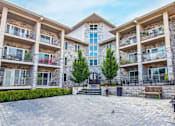 Thumbnail 6 of 20 - A courtyard with a tree surrounded by apartment buildings.