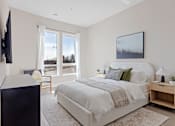 Thumbnail 2 of 24 - A bedroom with a large bed and a flat screen TV mounted on the wall at The Woods at 180 Kanata Avenue, Kanata, K2K 3L9