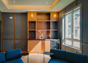 Thumbnail 25 of 39 - A living room with a blue couch and a wooden shelf.
