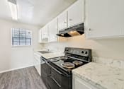 Thumbnail 45 of 55 - A kitchen with a black stove top oven and white cabinets.