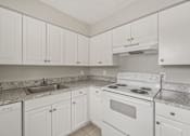 Thumbnail 4 of 39 - A kitchen with white cabinets and a white stove top oven.
