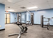 Thumbnail 22 of 33 - A gym with a variety of equipment including a treadmill, a stationary bike, and a weight bench.