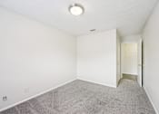 Thumbnail 41 of 55 - A room with a carpeted floor and a doorway leading to another room.