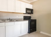 Thumbnail 3 of 12 - a kitchen with white cabinets and black appliances  at North Washington Apartments