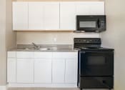 Thumbnail 4 of 12 - a kitchen with white cabinets and black appliances  at North Washington Apartments