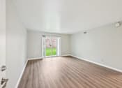 Thumbnail 7 of 55 - A room with a wooden floor and a sliding glass door leading to a balcony.