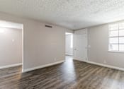 Thumbnail 6 of 20 - A room with wooden floors and a white door.