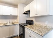 Thumbnail 4 of 20 - A kitchen with granite countertops and white cabinets.