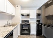 Thumbnail 3 of 20 - A kitchen with a black oven and white cabinets.